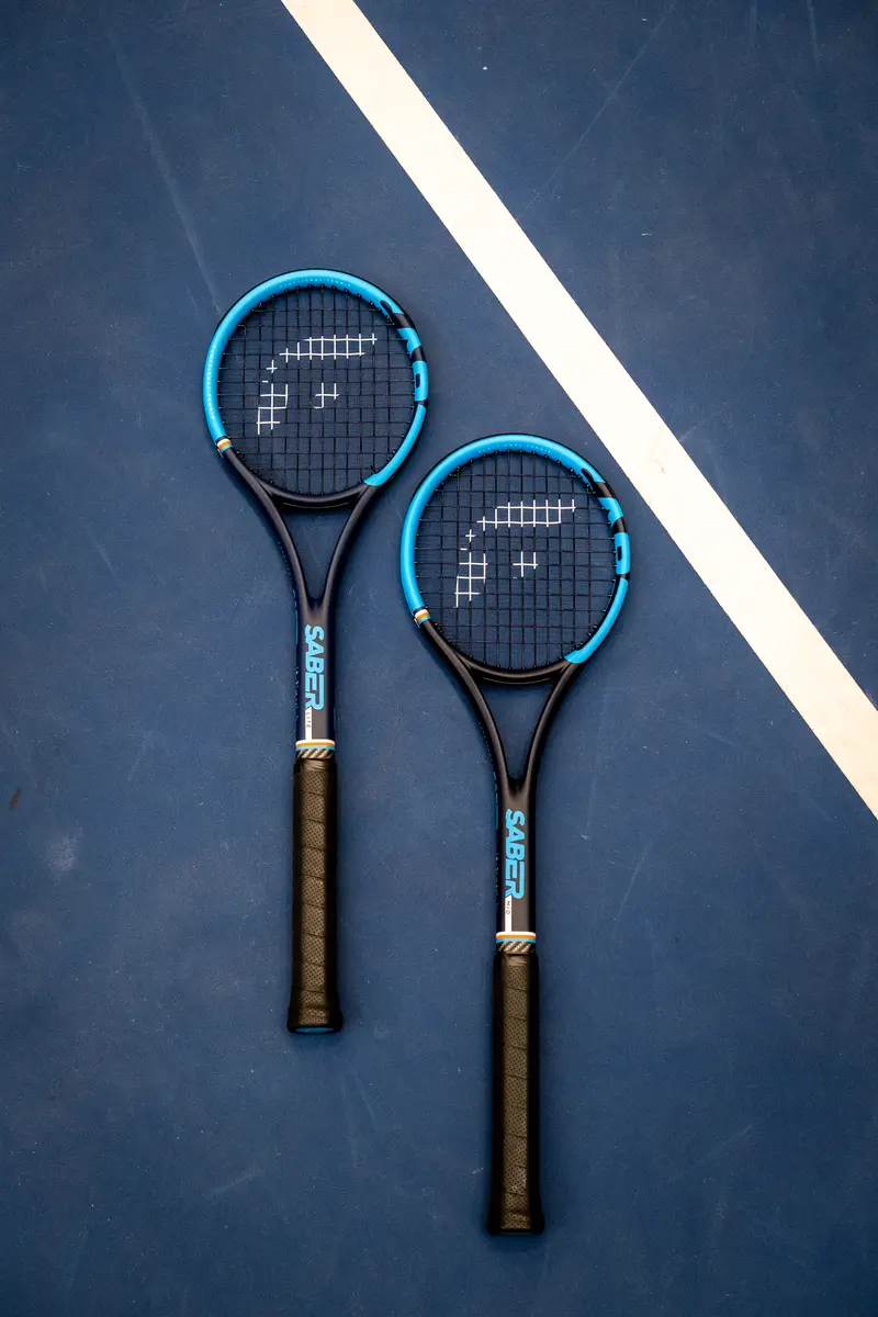 Two Functional Tennis Sabers with blue frames lying on a blue hard court